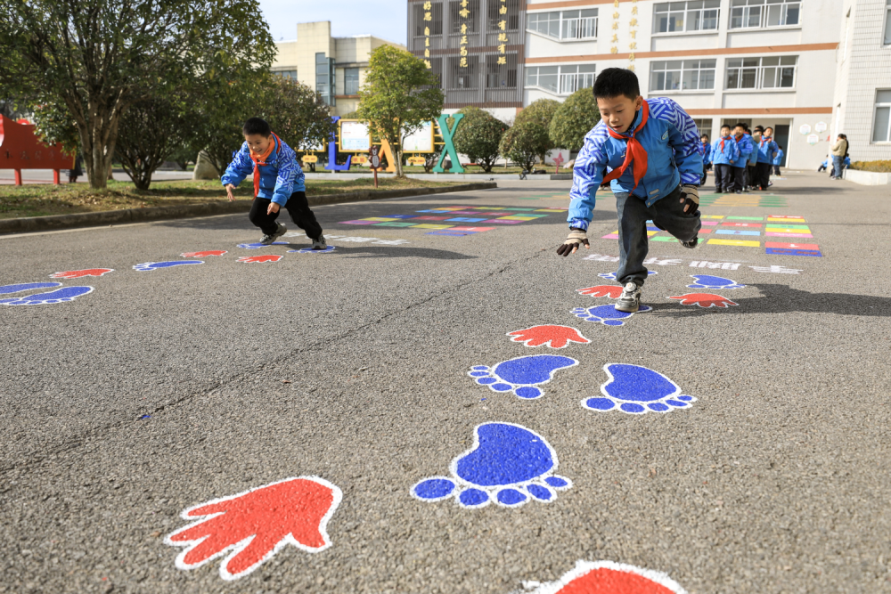 小学因地制宜,在教学楼前空地设置跳房子,青蛙跳,折线跑,手脚并用等